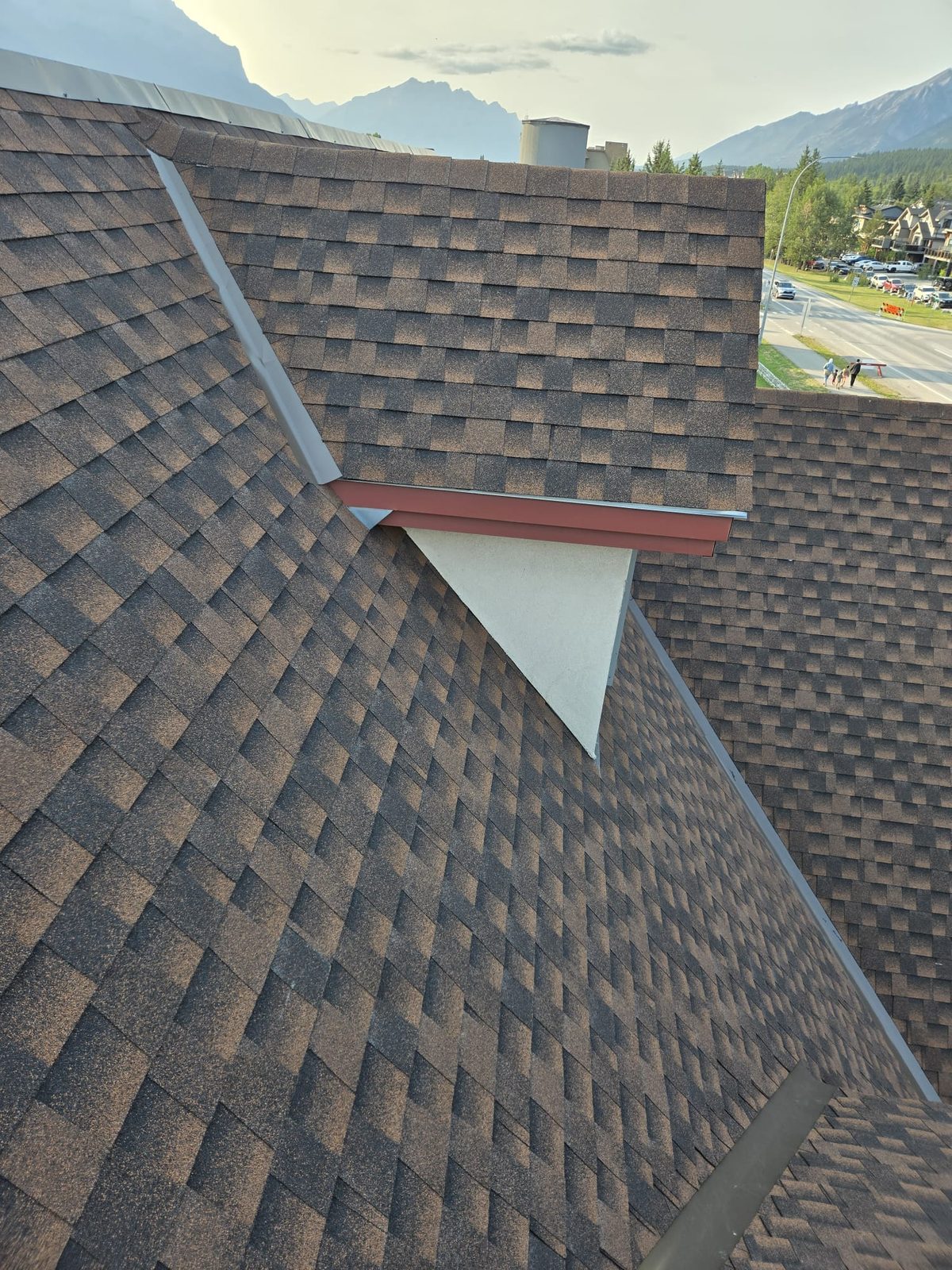 Brown shingles with metal flashing against a stucco gable