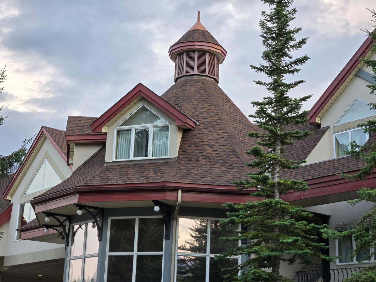 Shingled cupola and dormer roof with red trim on a large building