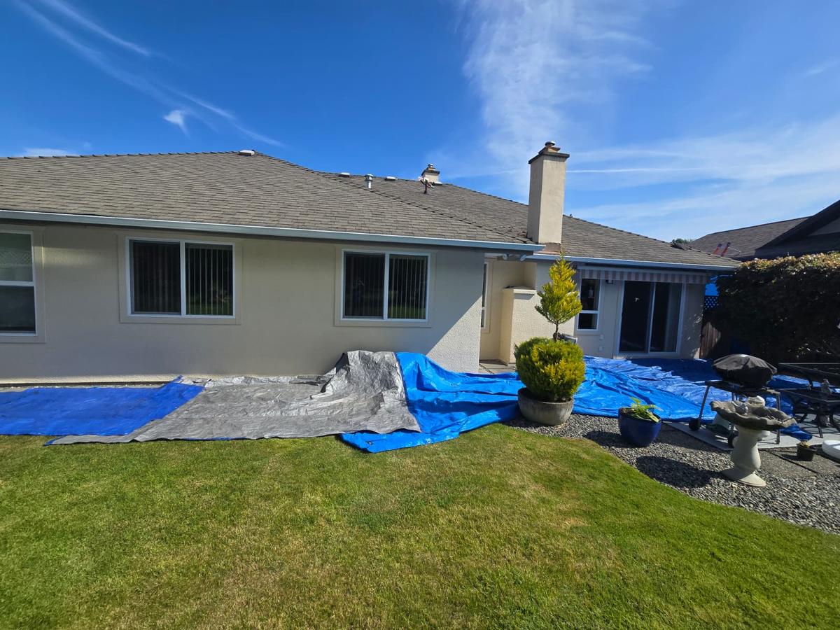Low-slope home roof with the yard covered in tarps to protect it during work