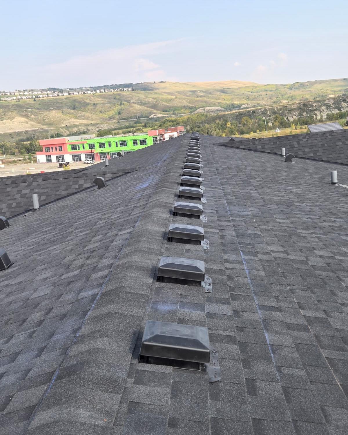 Long roof ridge with a row of ridge vents on dark shingles