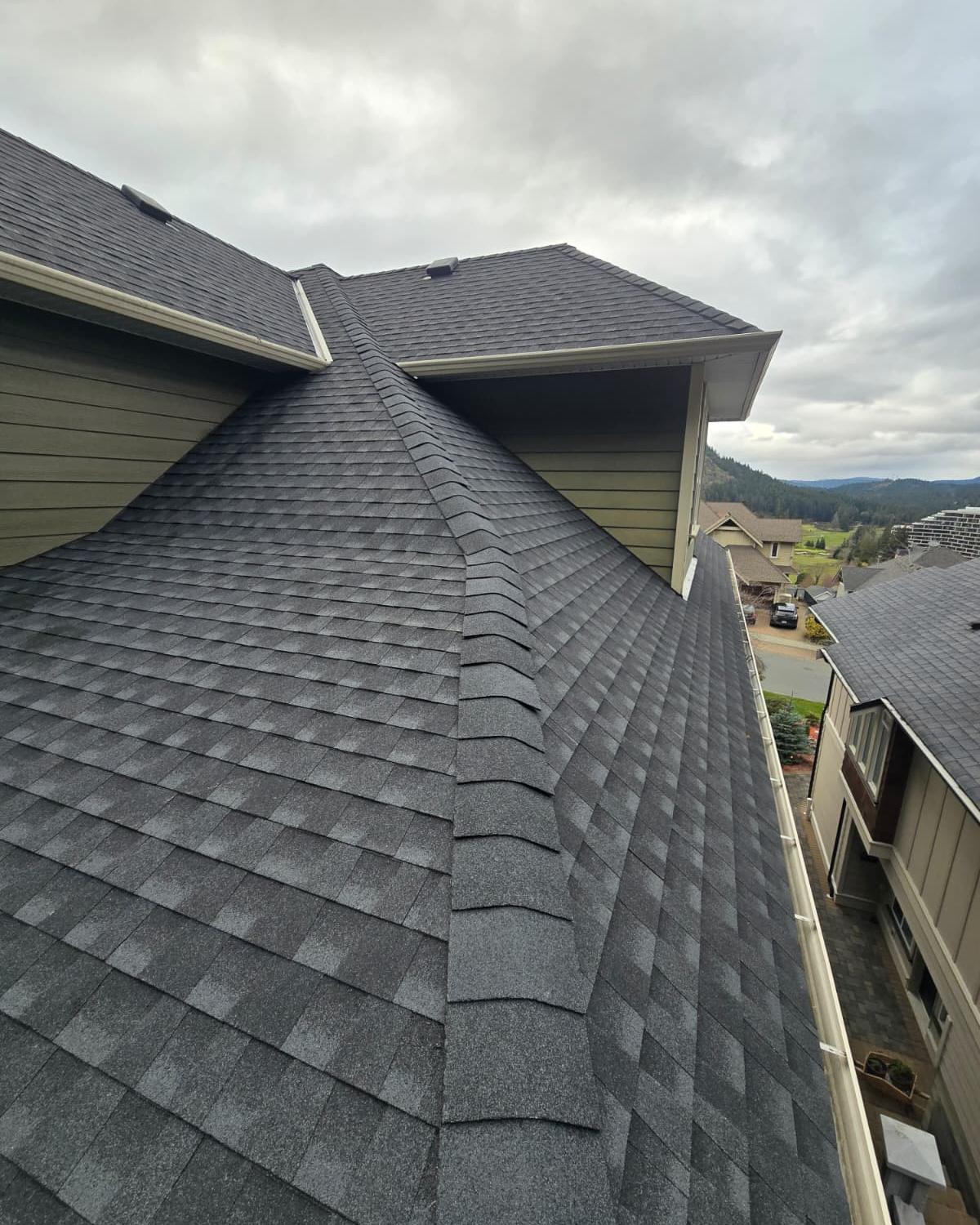 Finished dark grey shingle roof with a clean valley and ridge
